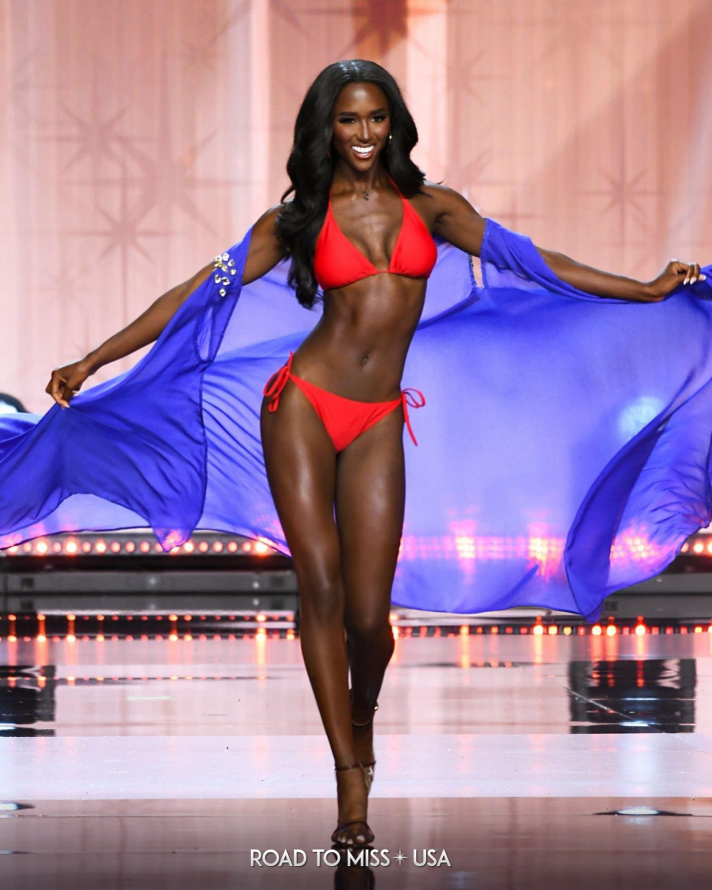 Aarieanna Ware on stage in a red swimsuit at the Miss Texas USA competition.